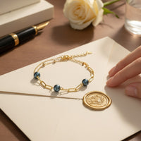 Ajura Pearls minimalist bracelet with dark blue freshwater pearls on a gold-plated chain with link and bead details.