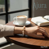 Ajura Pearls bracelet with freshwater pearls and a gold clover charm with a diamond accent.