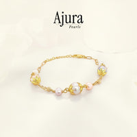 Ajura Pearls bracelet with freshwater pearls in white and peach, gold-plated chain and decorative accents.