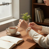 Ajura Pearls white freshwater pearl bracelet with gold chain and charm. Elegant layered design.